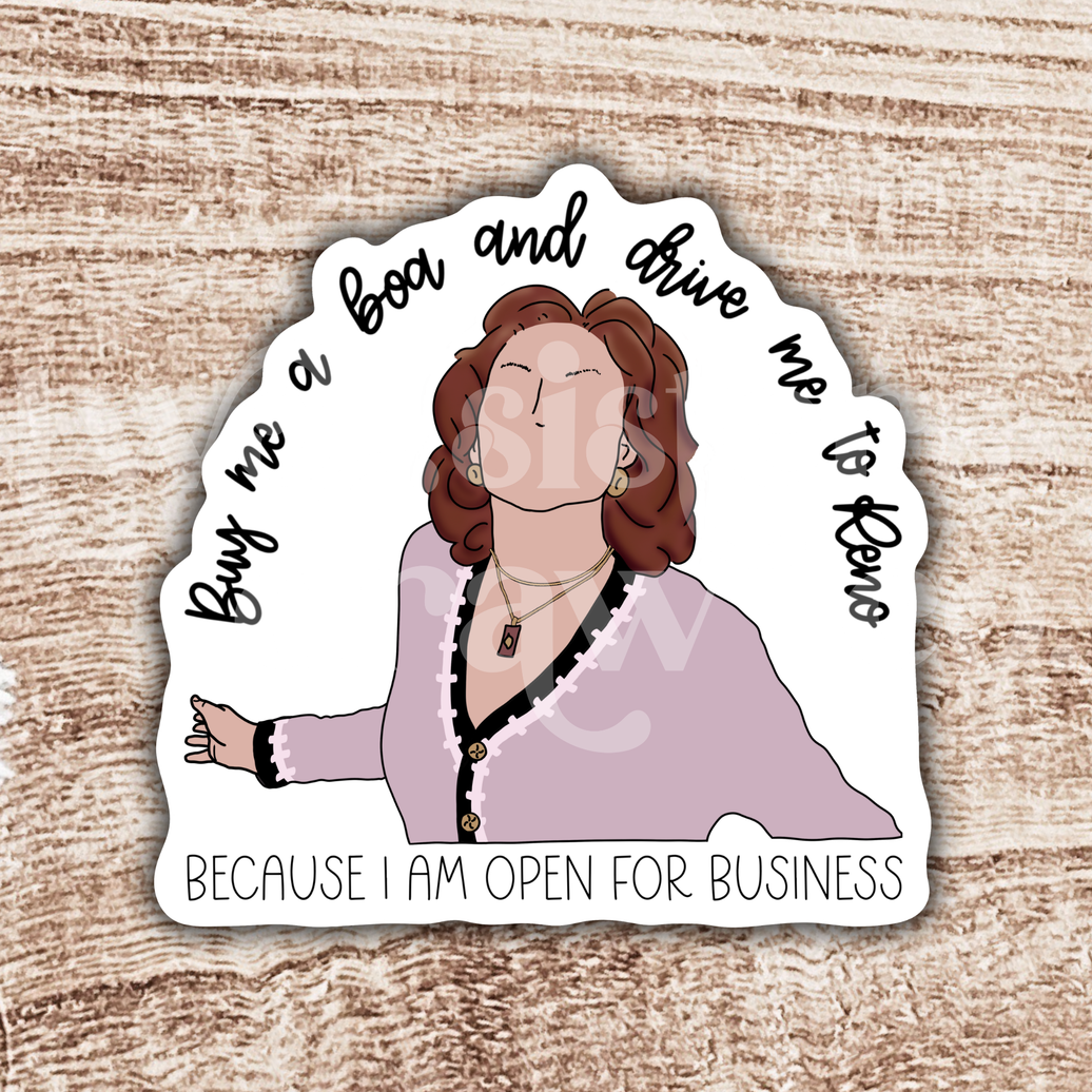 Illustrated Emily Gilmore sticker with "buy me a boa and drive me to Reno because I am open for business" quote in black script on a white background in front of a wood grain background.