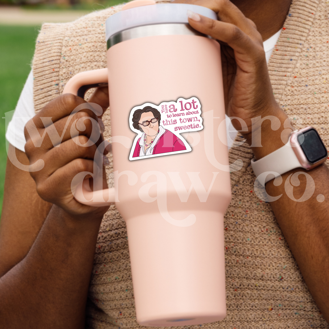 Person holding a tumbler with a h. and-drawn sticker of Phyllis Vance from The Office in a pink outfit and glasses with the text ‘you have a lot to learn about this town.