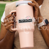 Person holding a tumbler with a Gilmore Girls sticker with the text 'a film by kirk' and a mini pig on top.
