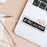Gilmore Girls sticker with the text 'a film by kirk' and a mini pig on top on a laptop.