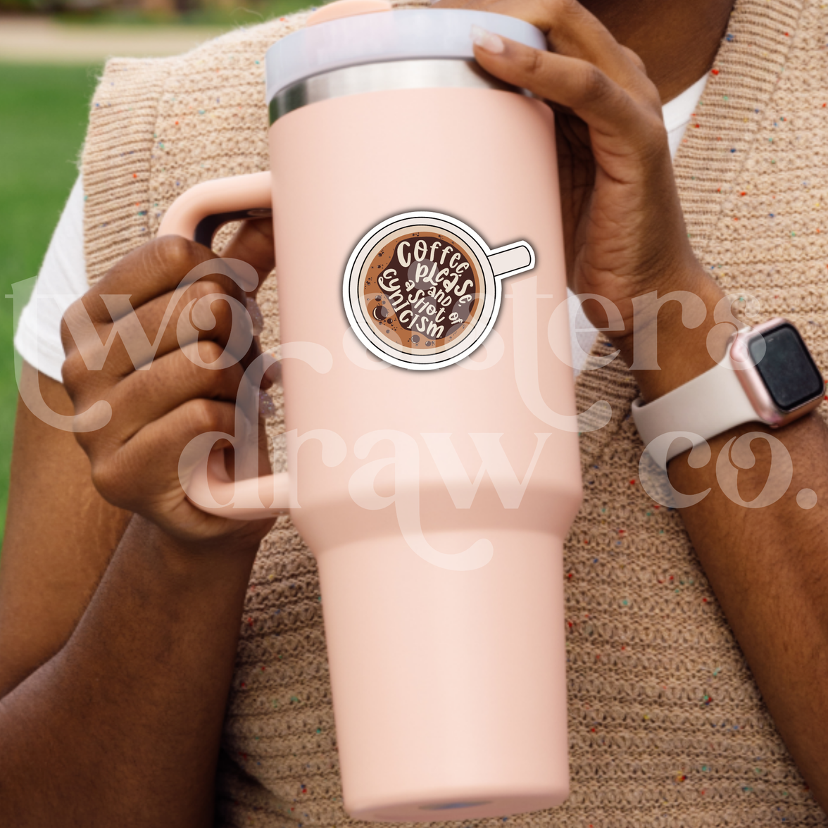 Person holding a tumbler with an hand-drawn illustration of a coffee cup sticker with text 'Coffee please and a shot of cynicism.’