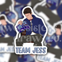 Sticker of Jess Mariano sitting on a bench reading with 'Team Jess' text with a patterned background.