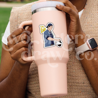 Person holding a tumbler with a hand-drawn sticker of Luke Danes pouring coffee with the text ‘Team Luke.’