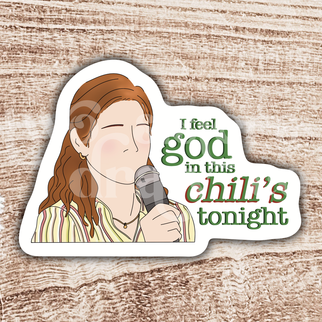 Hand-drawn sticker of Pam Beesley with a microphone and the text ‘I feel God in this Chili’s tonight’ on a wooden background.