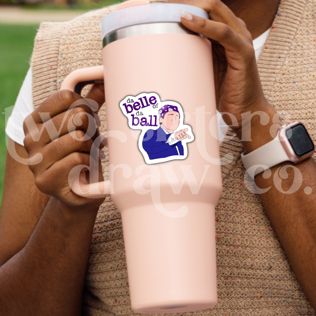 Person holding a tumbler with a hand-drawn sticker of Michael Scott pointing and wearing a purple bandana with the text 'da belle of da ball.’