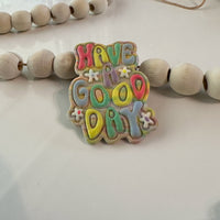 Close-up of handmade, polymer clay magnets featuring 3D bubble lettering  that says 'have a good day' with tiny white flower accents in sherbet colors on a white background with wooden beads.